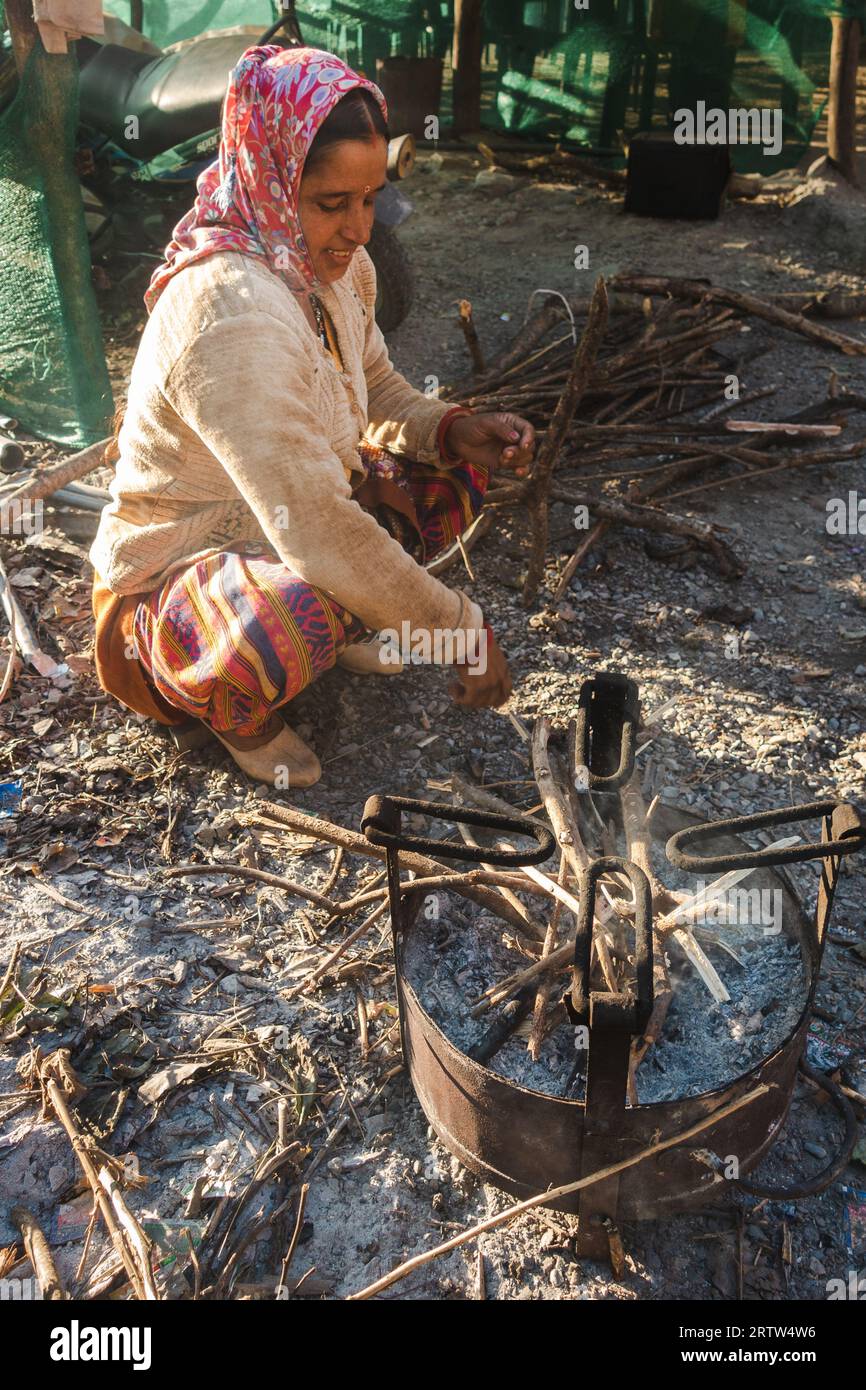 November 30th 2022. Tehri Garhwal, Uttarakhand India. Garhwali woman kindling fire in outdoor cast iron stove, rural Uttarakhand village, winter scene Stock Photo