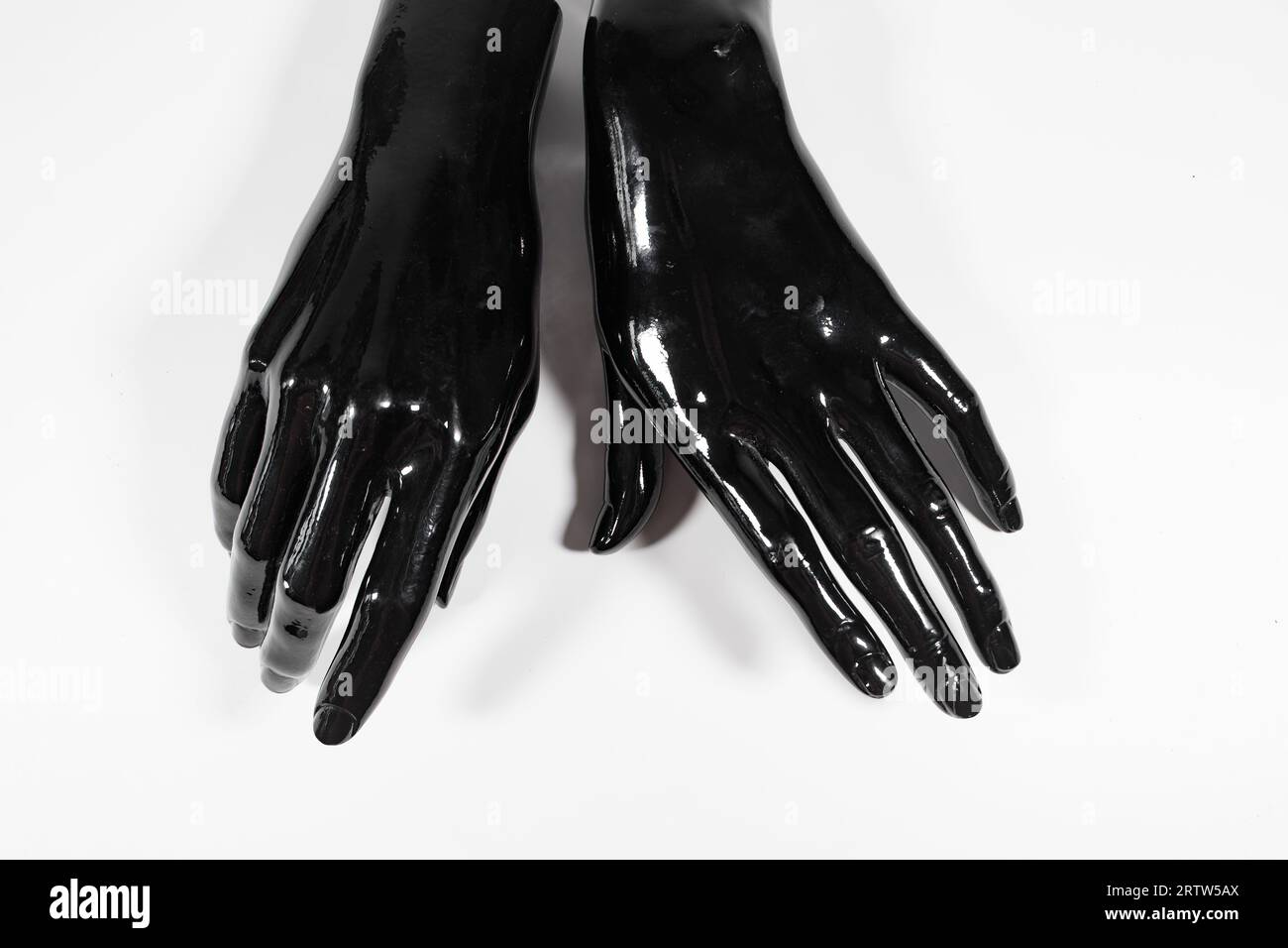 two shiny black female mannekin model hands against white studio background concept african american racial Stock Photo