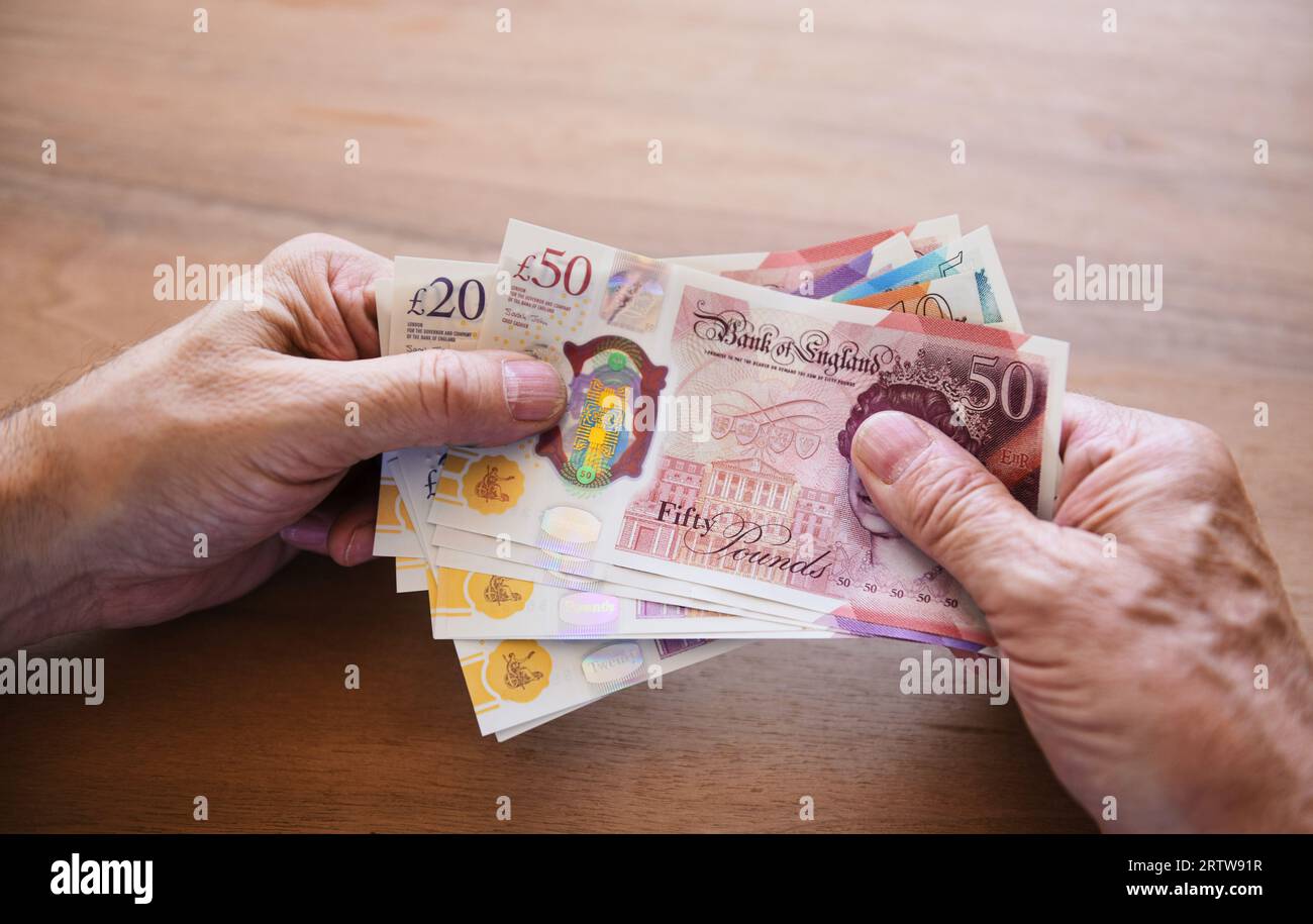 Holding British pound notes Stock Photo