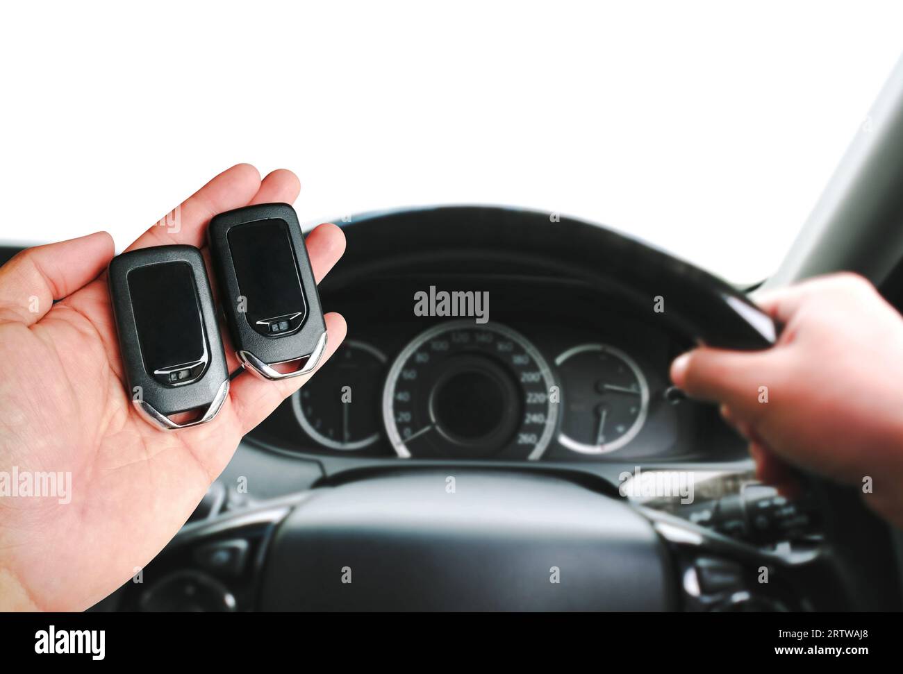 Driver hand holding a car keyless entry remote for engine start or stop. Two keyless car remotes in the driver hand for comparison. copy space, Concep Stock Photo