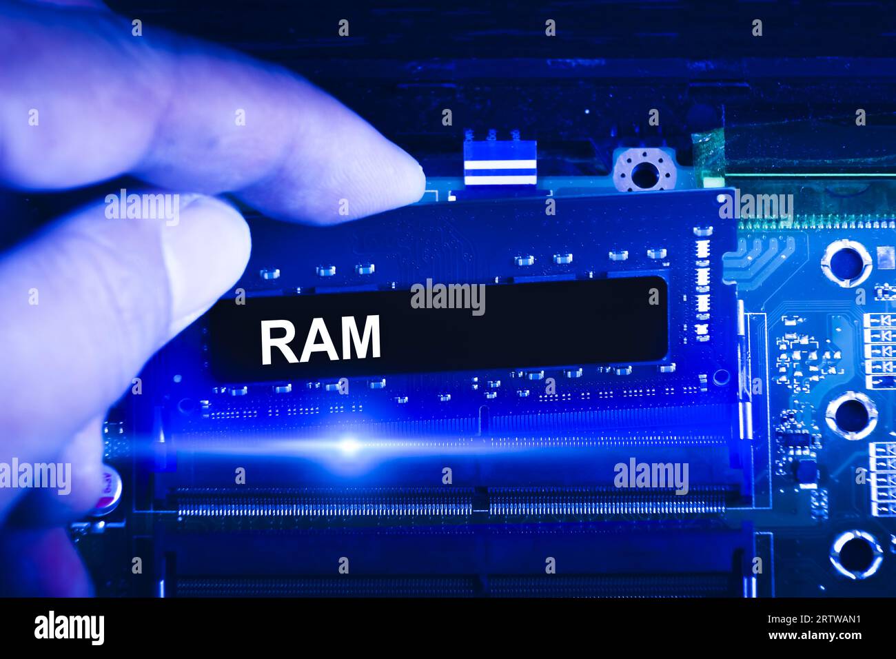 Technician hand insert RAM memory to memory slot on computer motherboard. Technician upgrade RAM memory into laptop. blue tone. Stock Photo