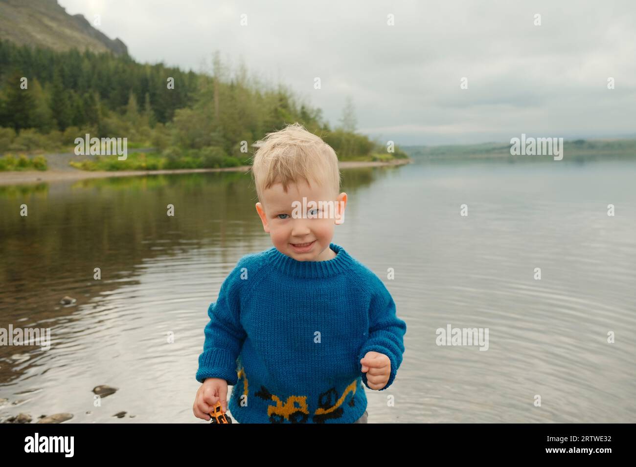 Toddler boy on shore of calm lake Stock Photo