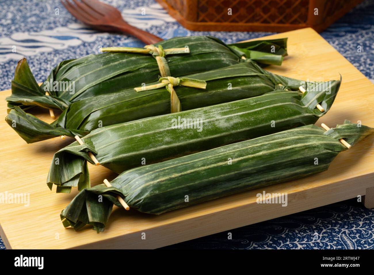 Whole Lemper Ayam wrapped in banana leaves, an Indonesian savoury snack made of glutinous rice filled with seasoned shredded chicken close up Stock Photo