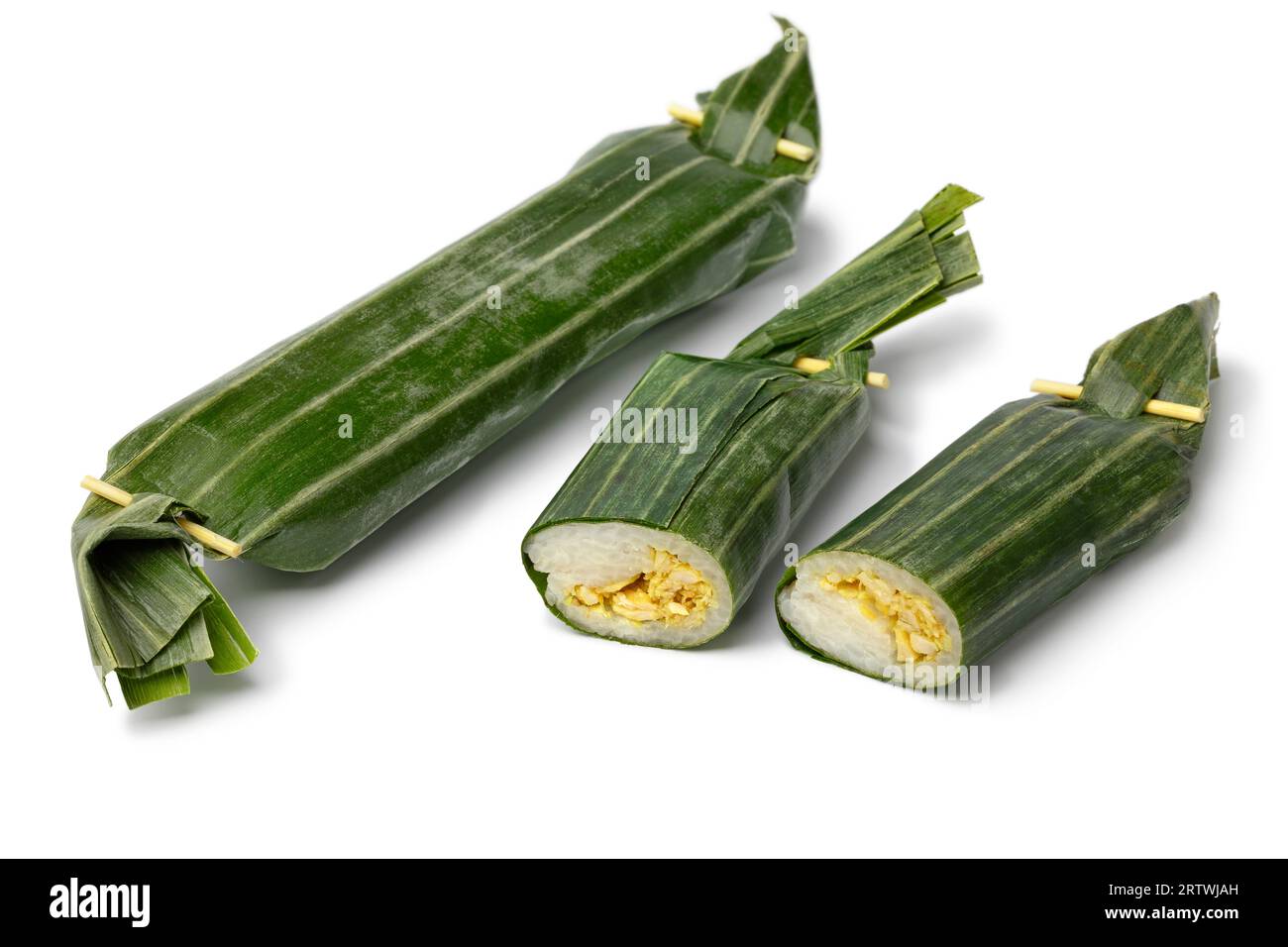 Whole and halved Lemper Ayam wrapped in banana leaves, an Indonesian savoury snack made of glutinous rice filled with seasoned shredded chicken close Stock Photo