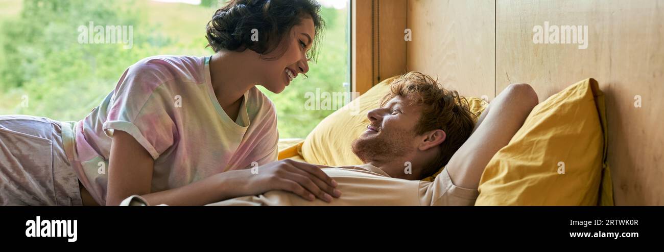 happy asian woman looking at boyfriend, interracial couple waking up in country house, banner Stock Photo