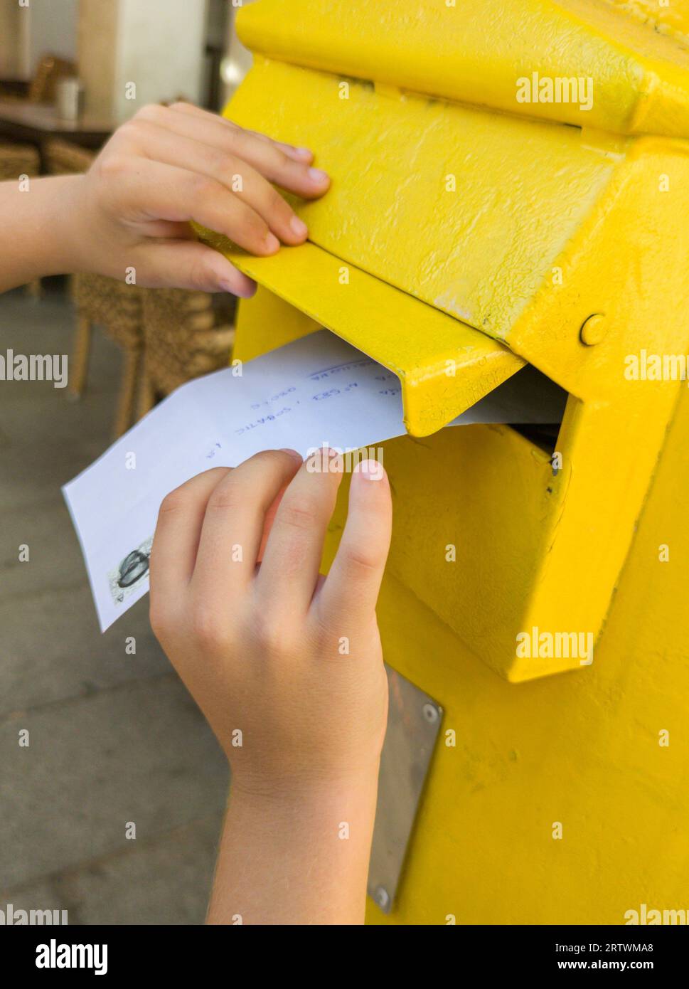 Boy putting a letter in the spanish yellow traditional mailbox. Selective focus. Stock Photo