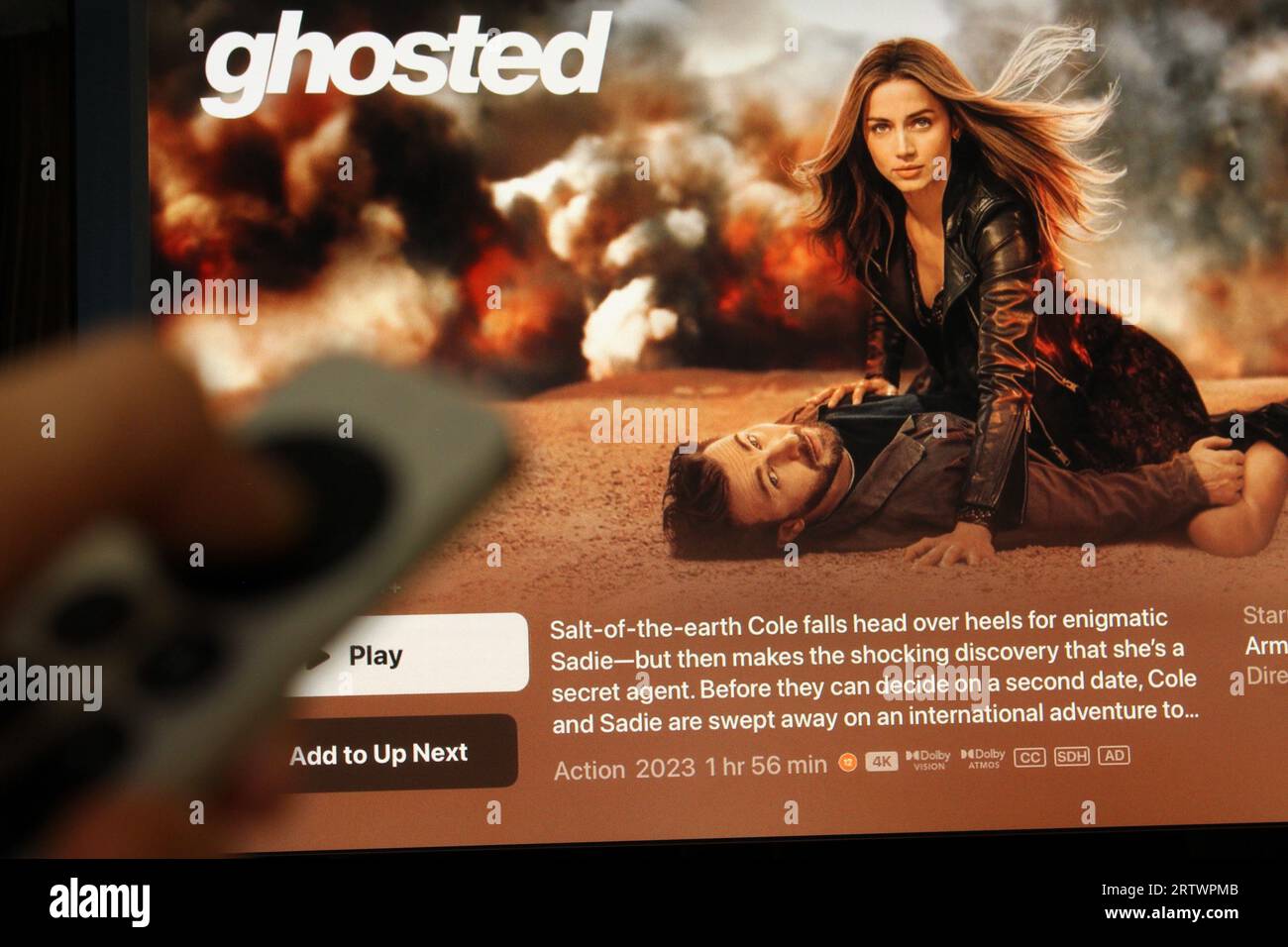 Apple TV plus app on a tv screen highlighting the Apple film Ghosted with the shadow of someone holding a remote. Concept for home entertainment Stock Photo