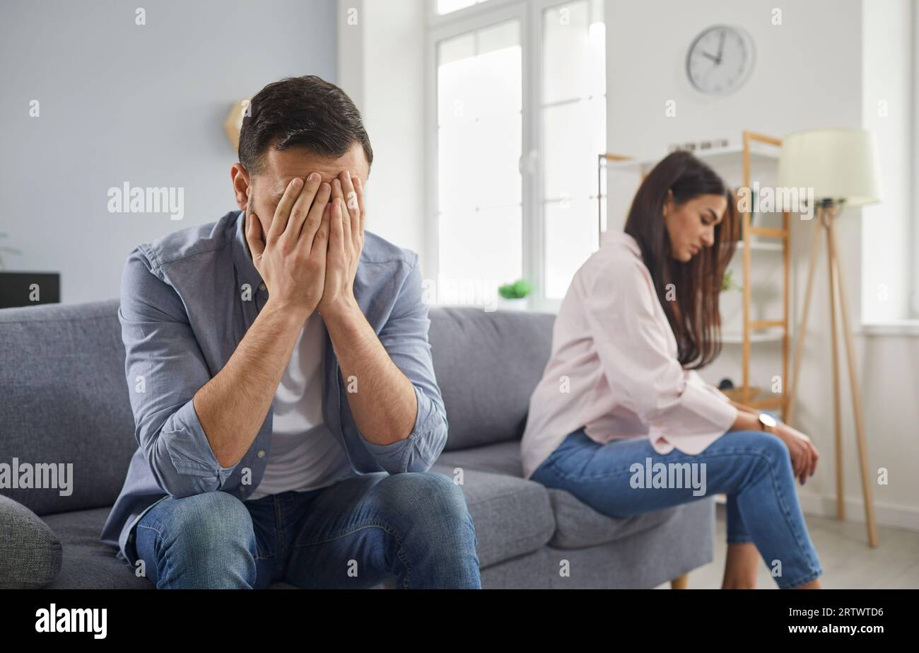 Upset married couple sitting silently on sofa facing away from each other Stock Photo