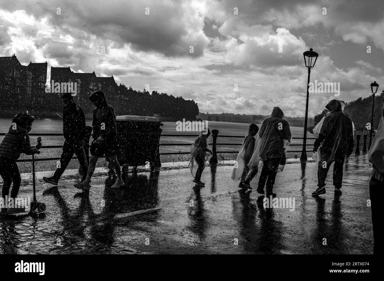 Lagan Walkway, Belfast, Northern Ireland August 06 2023 - Families caught in the rain wearing rain paunchos at the River Lagan Festival in Belfast Stock Photo