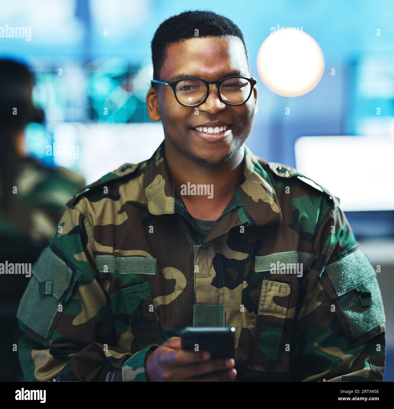 Portrait, phone and a military black man in a control room for surveillance, communication or networking. Face, smile and a confident young army Stock Photo