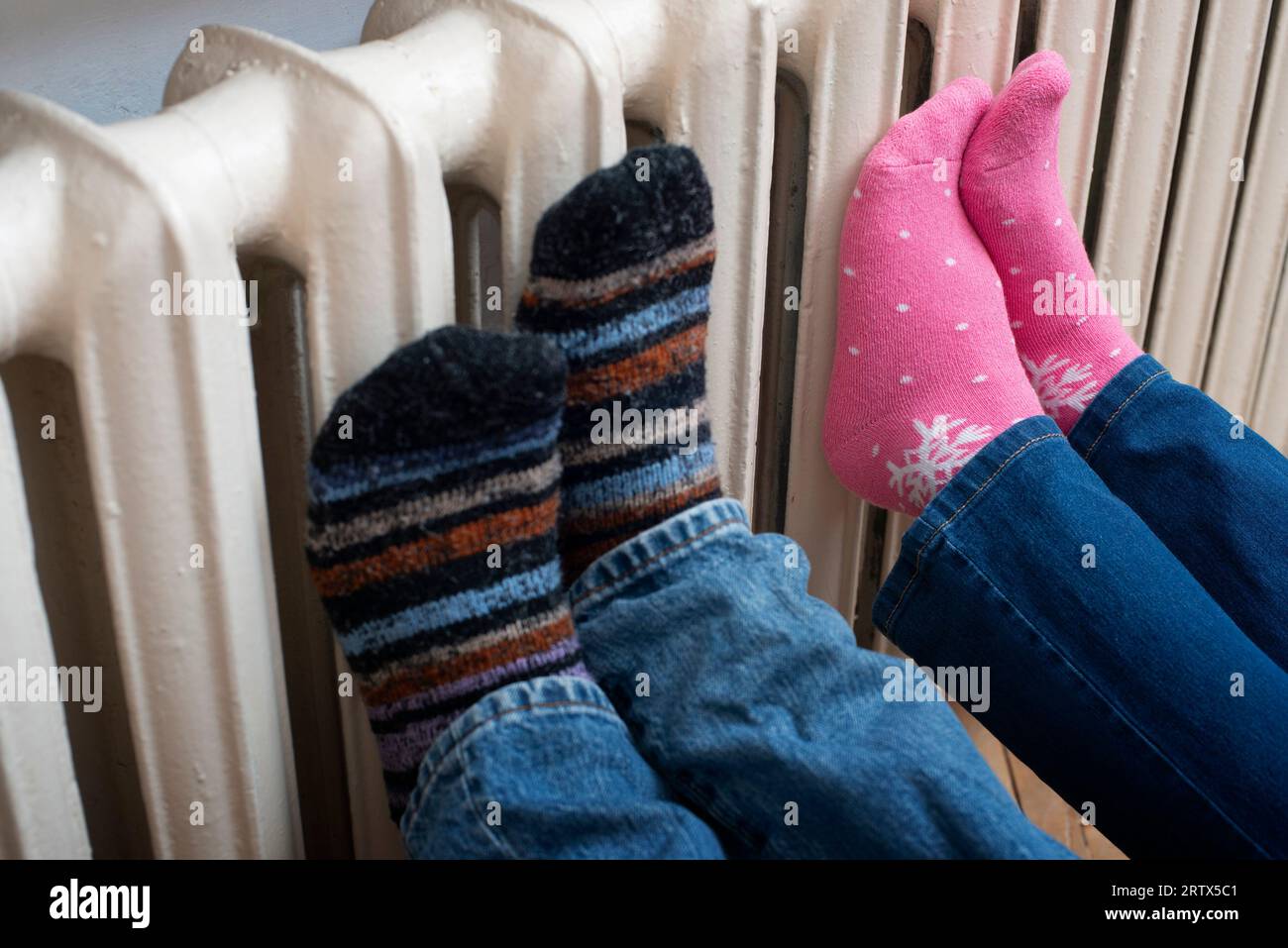 Couple warming up their feet on central heating radiator. Stock Photo