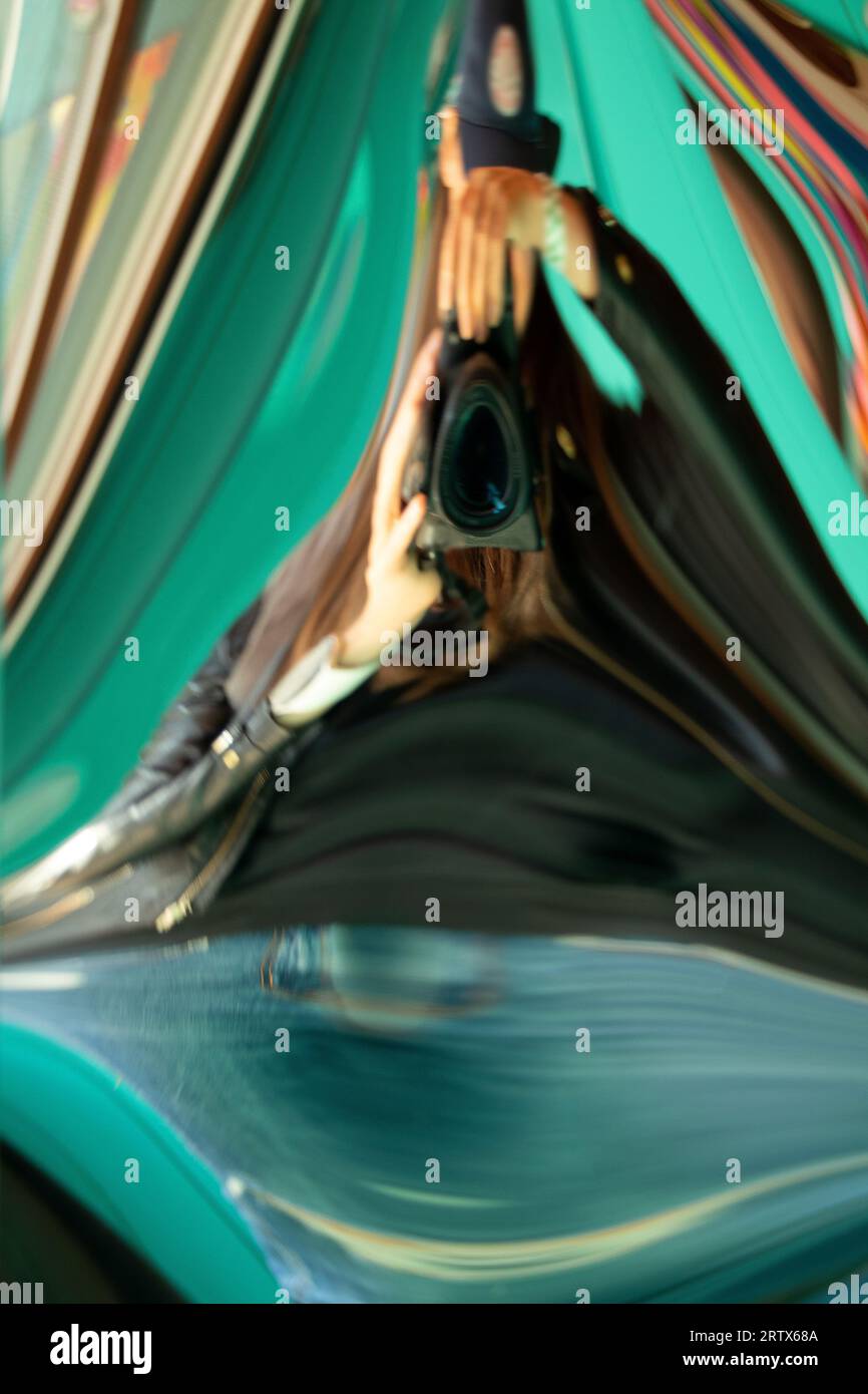 Girl photographer with a camera, distorted in a distorted mirror, a