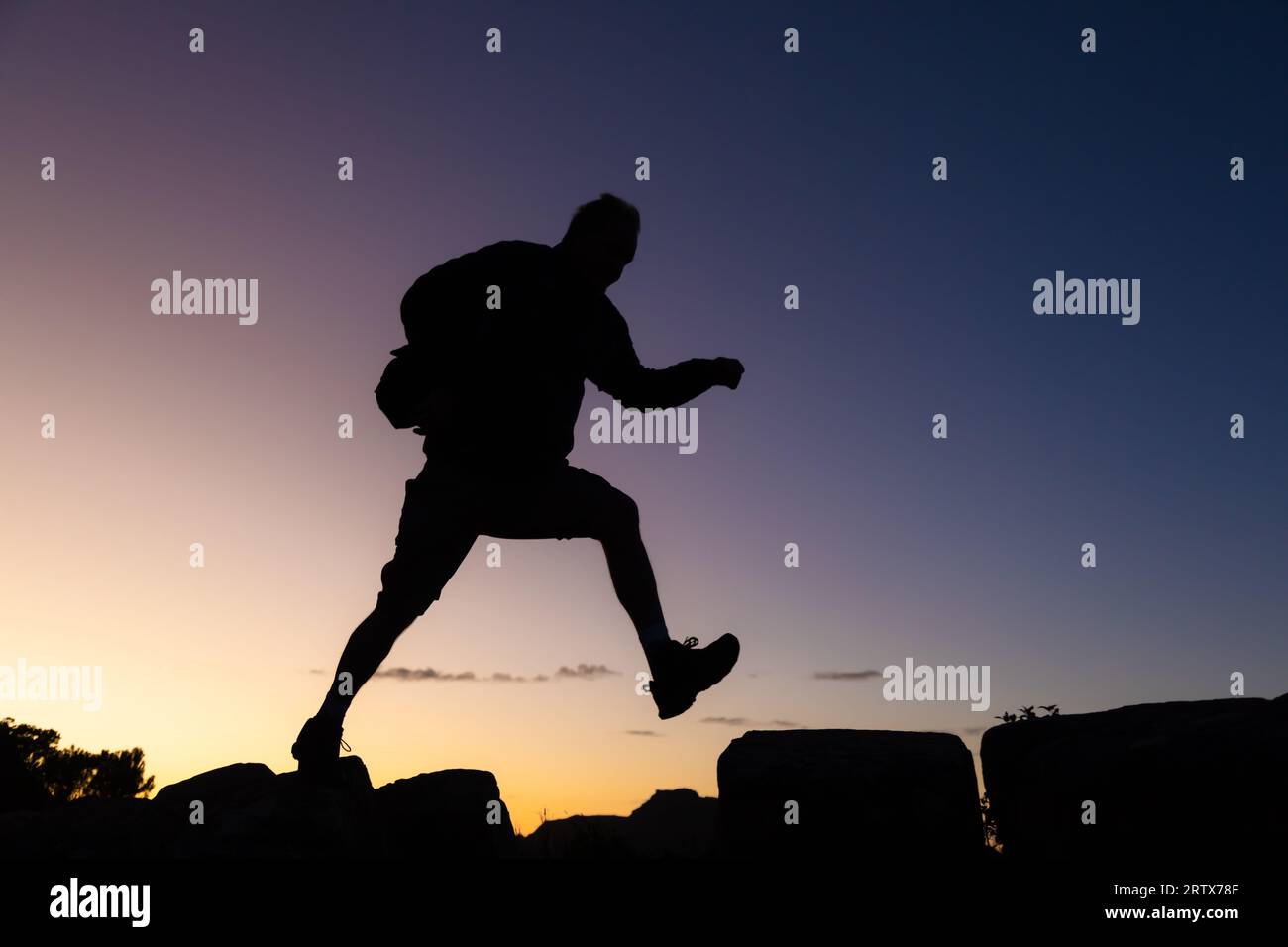 Senior citizen on a hike at sunrise in silhouette Stock Photo
