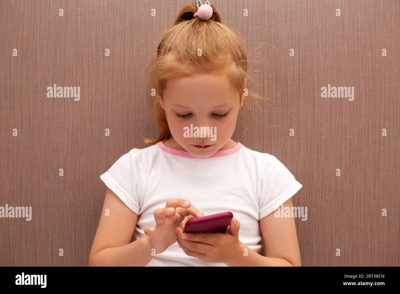 caucasian red haired girl with mobile phone, pretty kid girl using smartphone Stock Photo