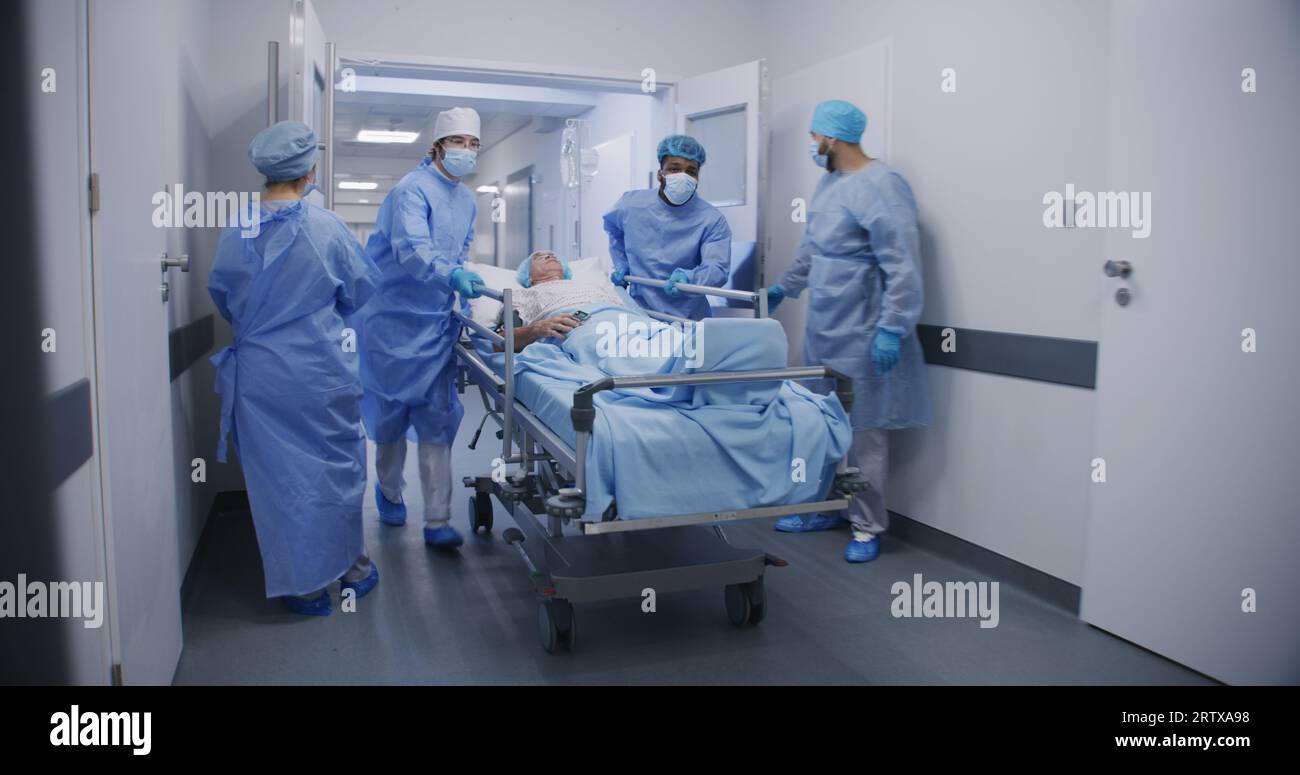 Multicultural doctors transport senior patient to operating room down