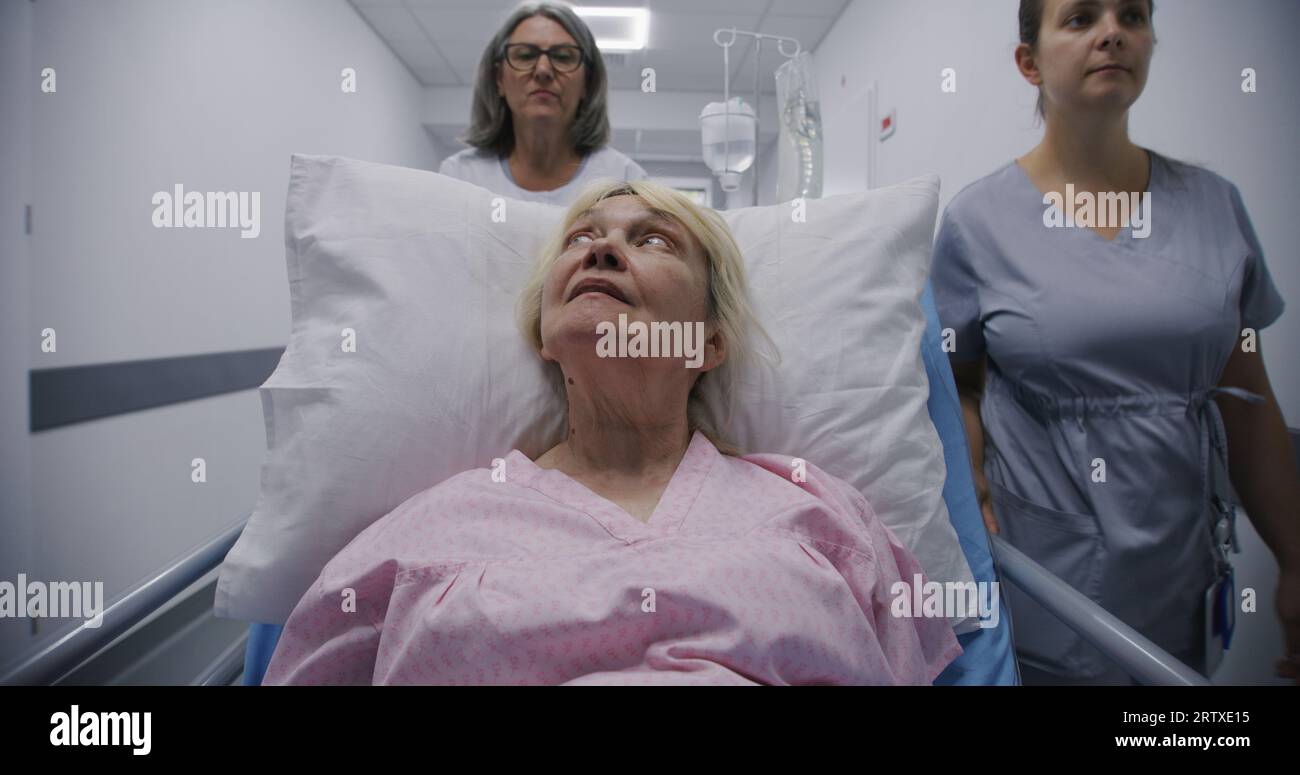 Mature female doctor with young nurse brings senior patient to medical