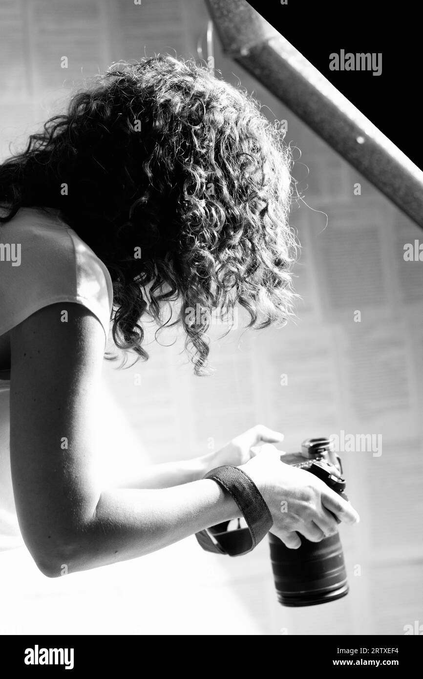 Profesional female photographer holding camera and taking photos .  Stock Photo