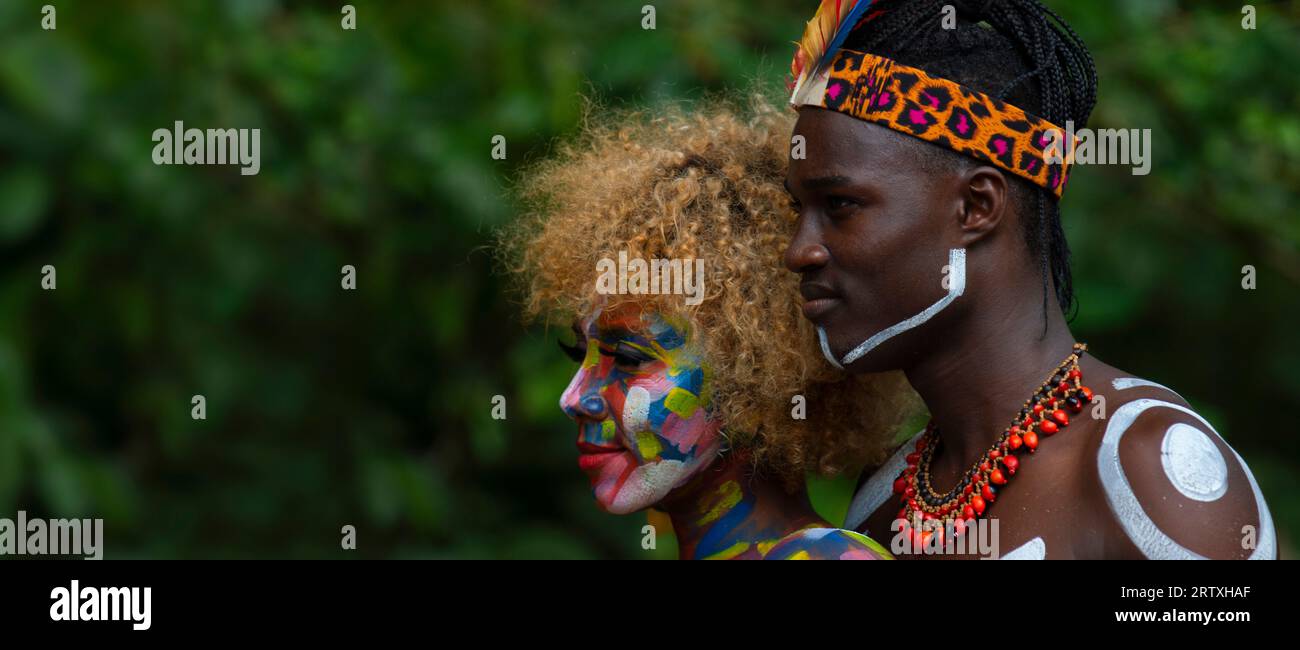 Nueva Loja, Sucumbios / Ecuador - September 3 2020: Profile portrait of young black couple with colorful painted faces embracing and smiling in a fore Stock Photo