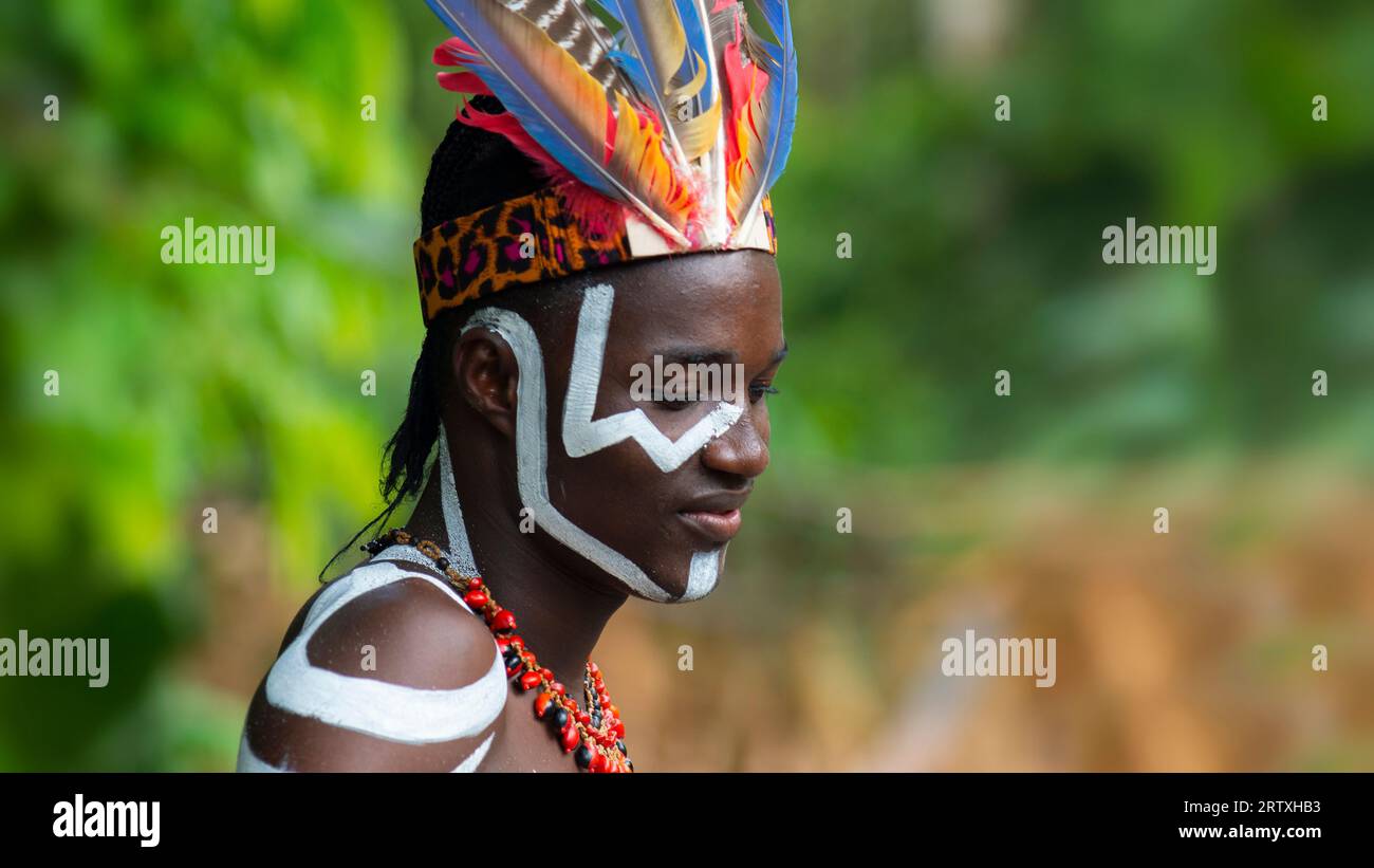 Nueva Loja, Sucumbios / Ecuador - September 3 2020: Profile portrait of young black man with body painted with white lines smiling in a forest with un Stock Photo