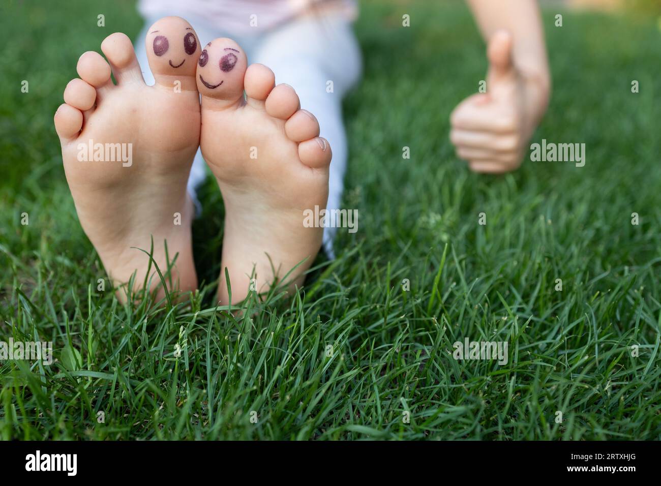 Children's bare feet on green grass. cheerful positive atmosphere, happy childhood, life in joy. Summer rest. prevention of orthopedic problems, foot Stock Photo