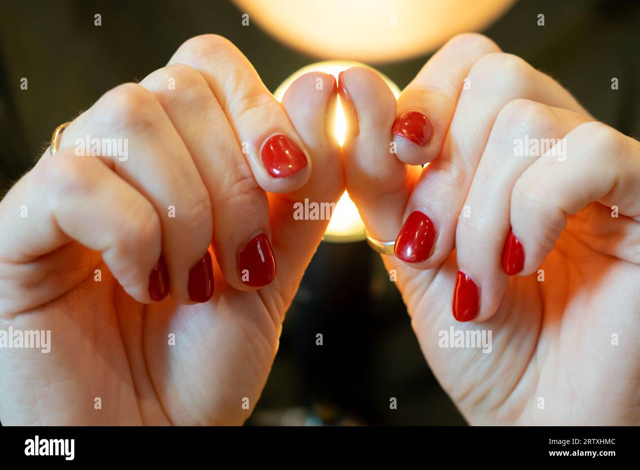Test for clubbed fingers, The Schamroth window test. Woman pushing her thumb nails together showing bright gap and passing the test. Red nail varnish. Stock Photo