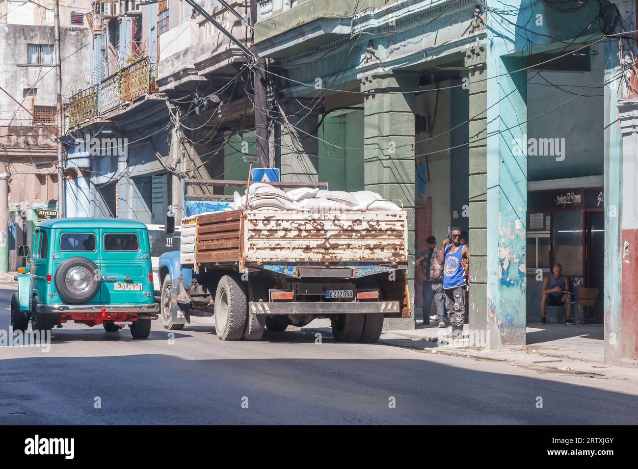 Havana, Cuba, 2023, An old vintage jeep drives by a truck on a city street. Transportation with obsolete motor vehicles is common in Cuba. Stock Photo