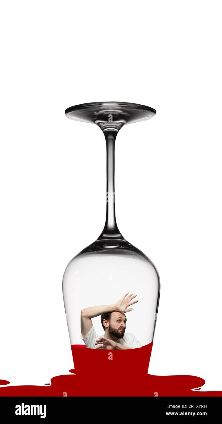 Young man diving into glass with red wine. Suffering from male alcoholism and problems