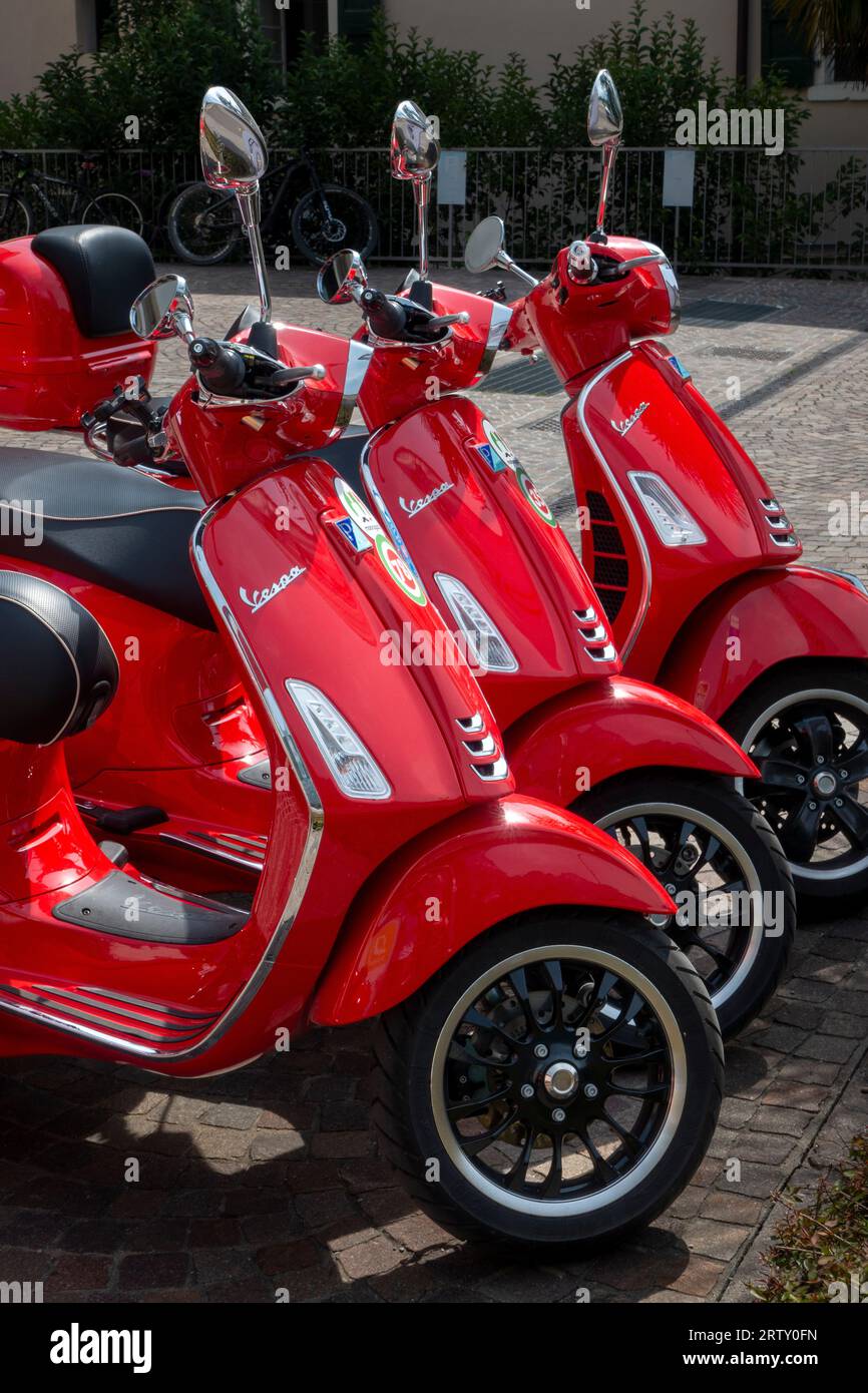 Three Red rental Vespa scooters, Riva, Rival del Garda, province of Trento of the Trentino Alto Adige region, Italy Stock Photo