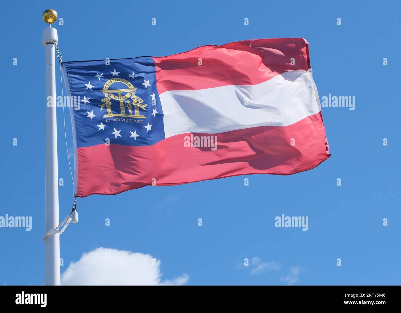Close up photo of Georgia state flag against a blue sky background Stock Photo