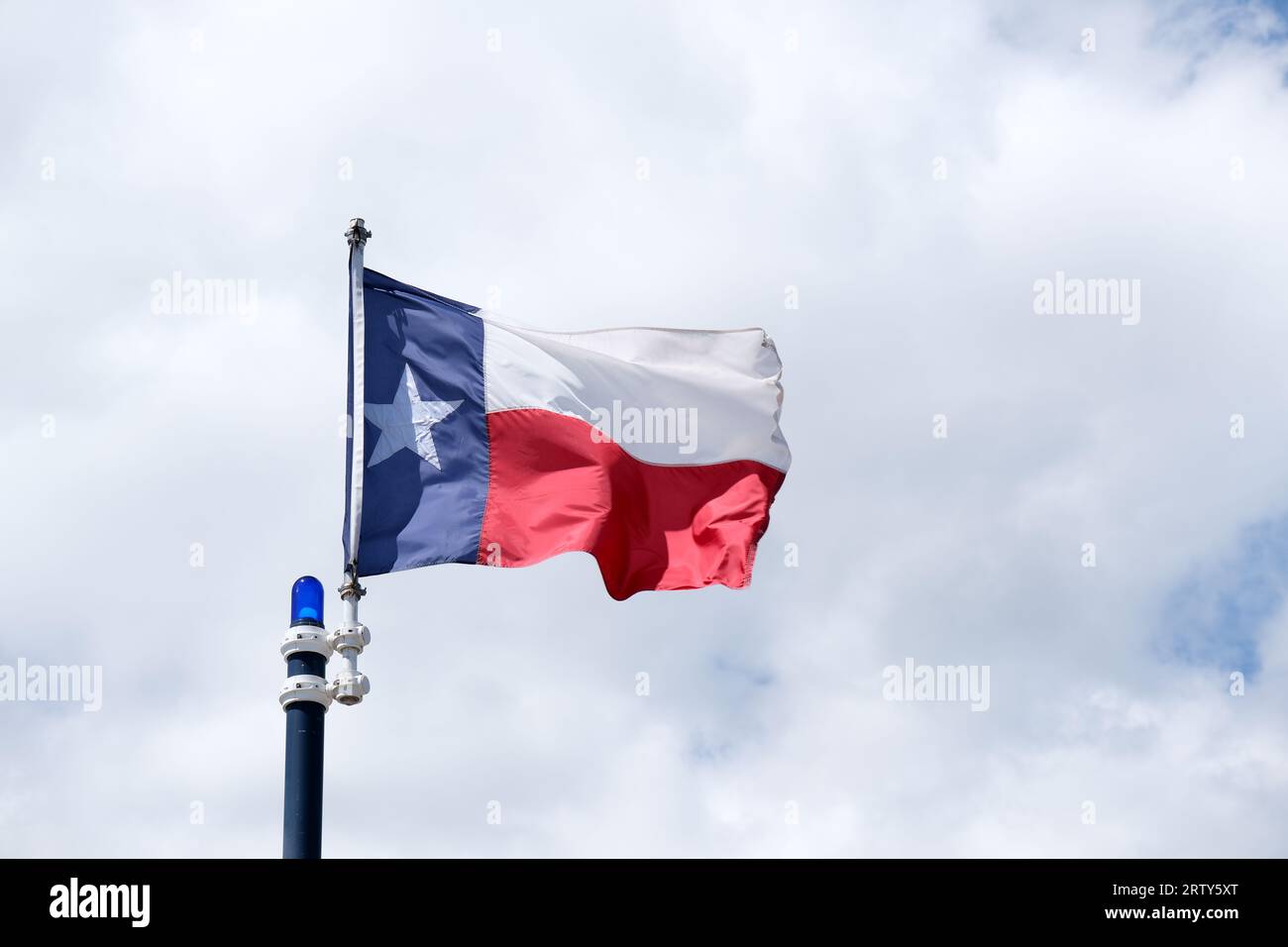 Texas state flag flying against a white cloud background Stock Photo