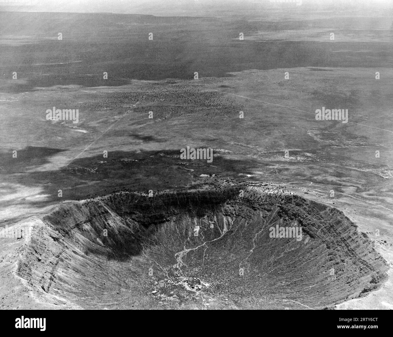 Winslow, Arizona  c. 1935  An aerial view of the Meteor Crater, caused by a meteor hitting there 200 years ago. The dark area is from a passing cloud. Stock Photo