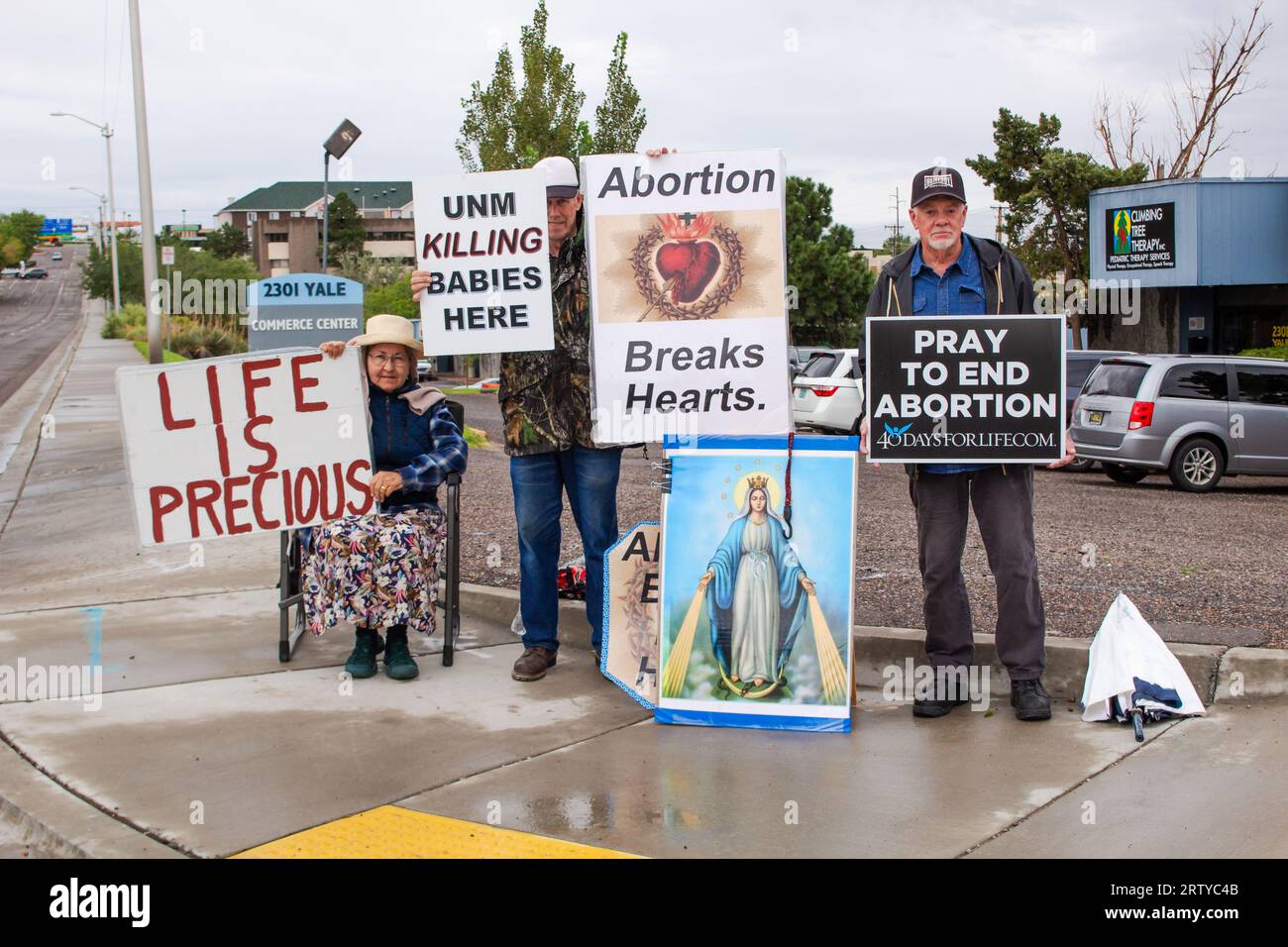 Senior protestors stand on street corner in Albuquerque, New Mexico, holding anti-abortion pro-life signs and a large image of Mother Mary. Stock Photo
