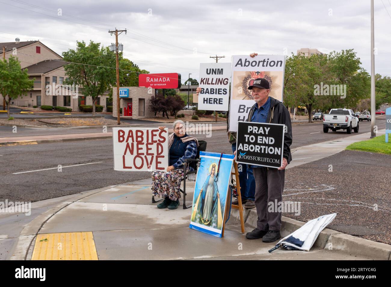 Senior protestors stand on street corner in Albuquerque, New Mexico, holding anti-abortion pro-life signs and a large image of Mother Mary. Stock Photo