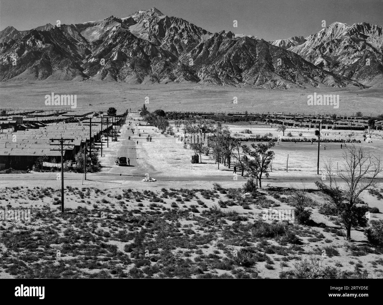 Owens Valley, California     1943 View from a guard tower of the Manzanar Relocation Center, one of the smaller Internment camps for Japanese-Americans. Photograph shows the western side of the grounds with the Sierra Nevada Mountains. At its peak, Manzanar held around 10,000 inmates, with the first inmates arriving in 1942, and the last leaving in 1945. Today, it is preserved as a National Historic Site. Photograph by Ansel Adams. Stock Photo