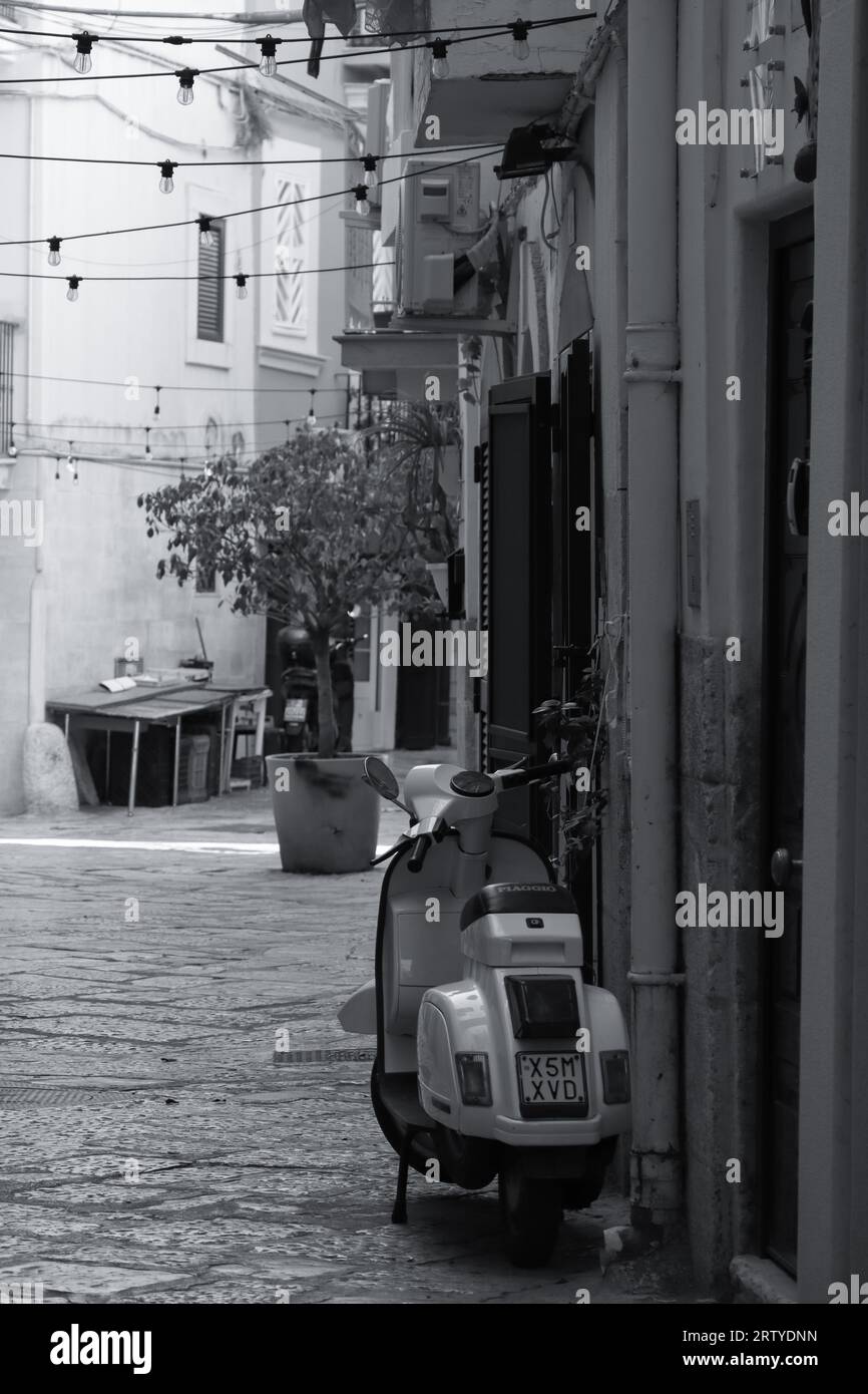 Vicolo della città vecchia di Bari che conduce alla strada delle orecchiette (Arco Basso). Veduta delle case con vespa parcheggiata e luci appese Stock Photo