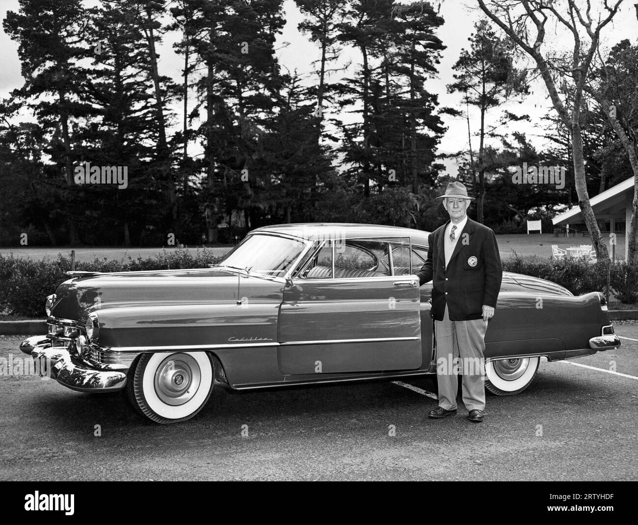 Pebble Beach, California  c. 1952 A man proudly standing next to his Cadillac Series 62 Coupe De Ville two door hardtop. Stock Photo