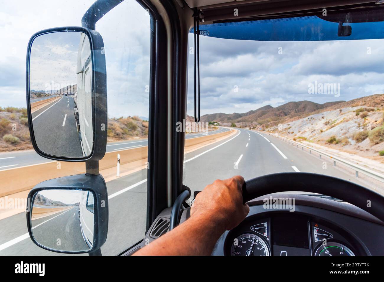 View from the driving position of a truck of the rearview mirror and the empty highway. Stock Photo