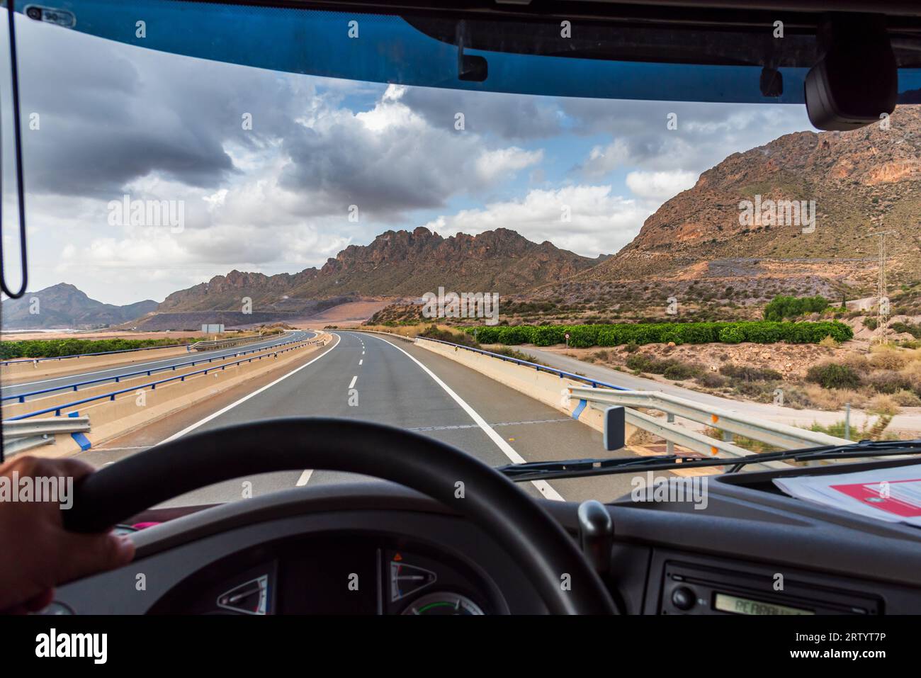 View from the driving position of a truck of the highway and a landscape of mountains in the background at dawn. Stock Photo