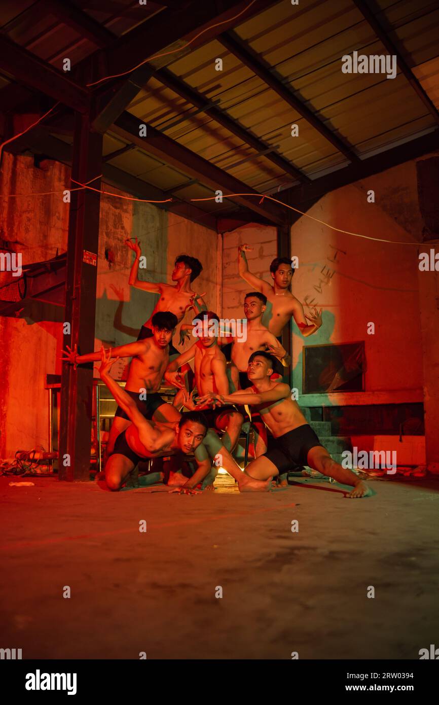 a group of men without clothes dancing poses in an old building with a red  light at night Stock Photo - Alamy