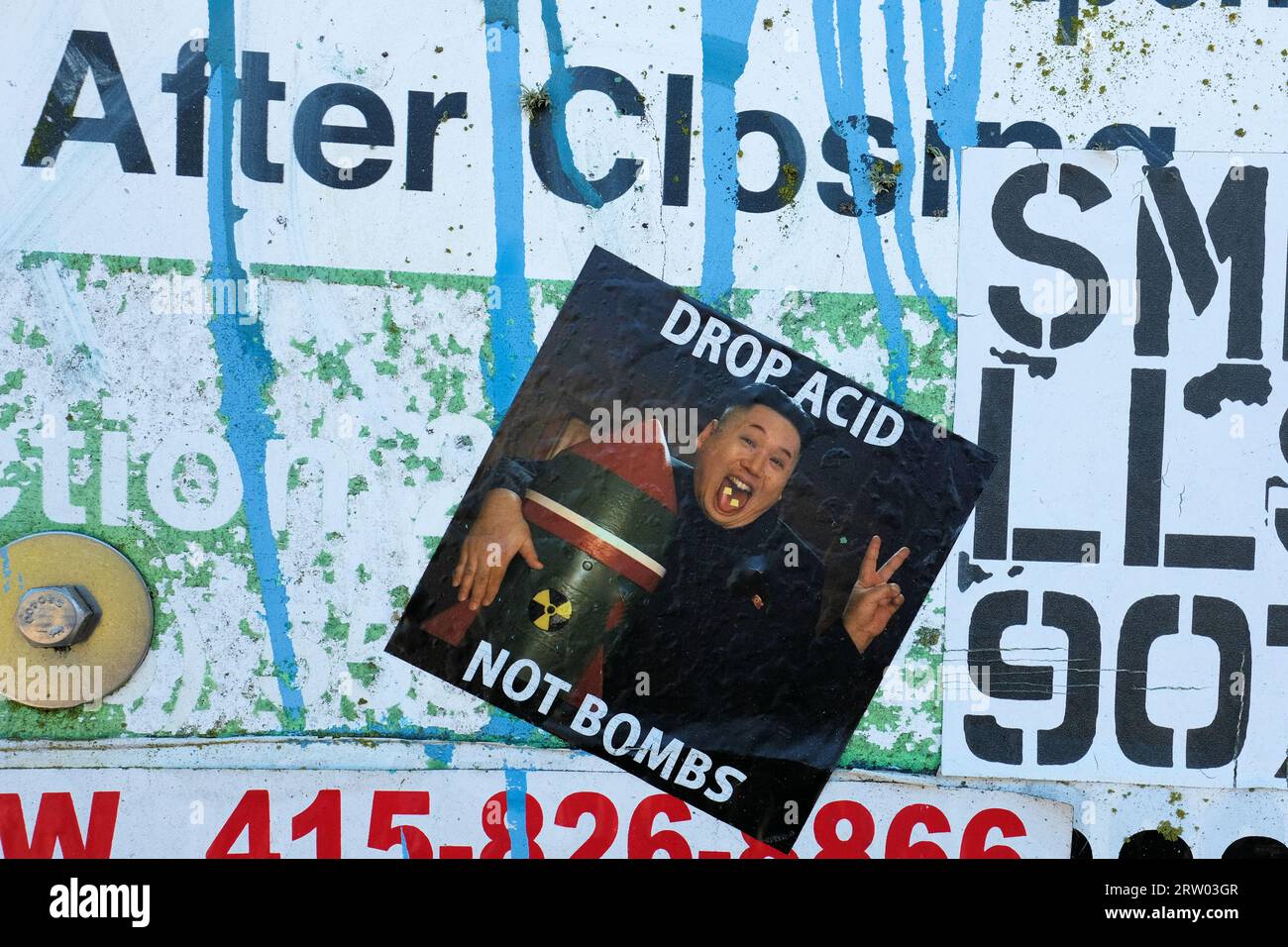 Sticker of North Korean ruler Kim Jong Un with acid tab on his tongue while hugging a nuclear warhead stating Drop Acid Not Bombs; San Francisco, CA. Stock Photo