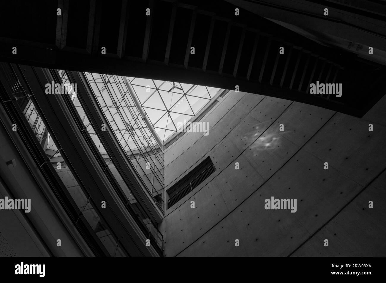 Black and white color and tone, Interior low angle diminishing perspective view at the atrium and skylight surround with curvature concrete. Stock Photo