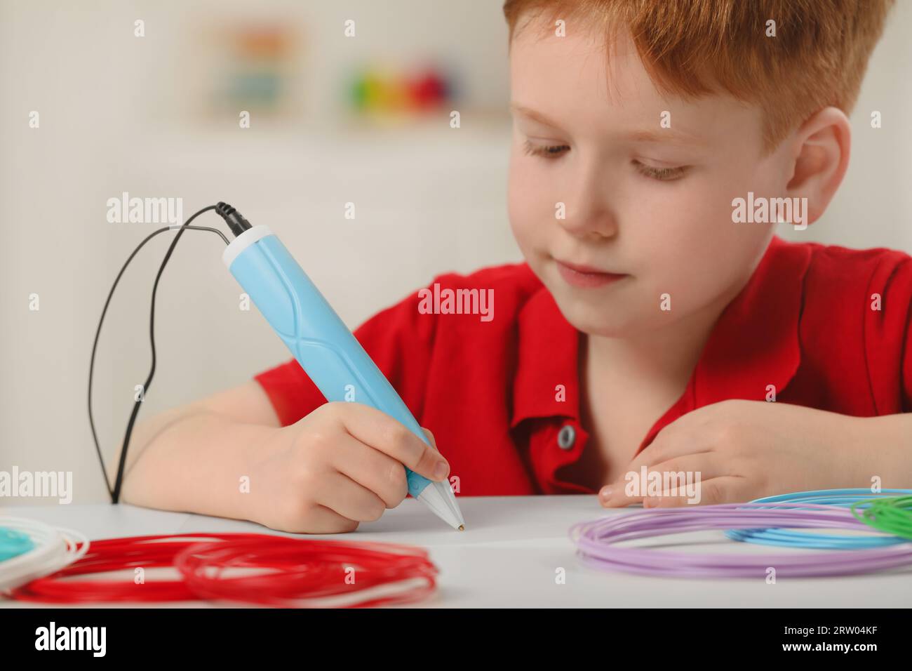 Boy drawing with stylish 3D pen at white table Stock Photo