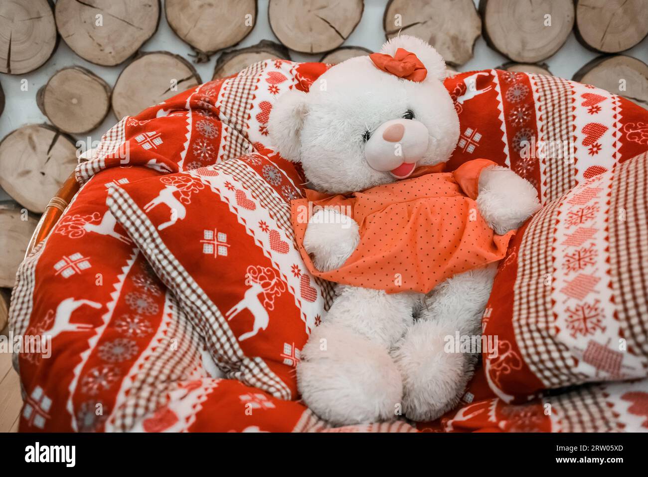 Soft fluffy toy bear girl in pillows and New Year's blanket on a rocking chair. Stock Photo