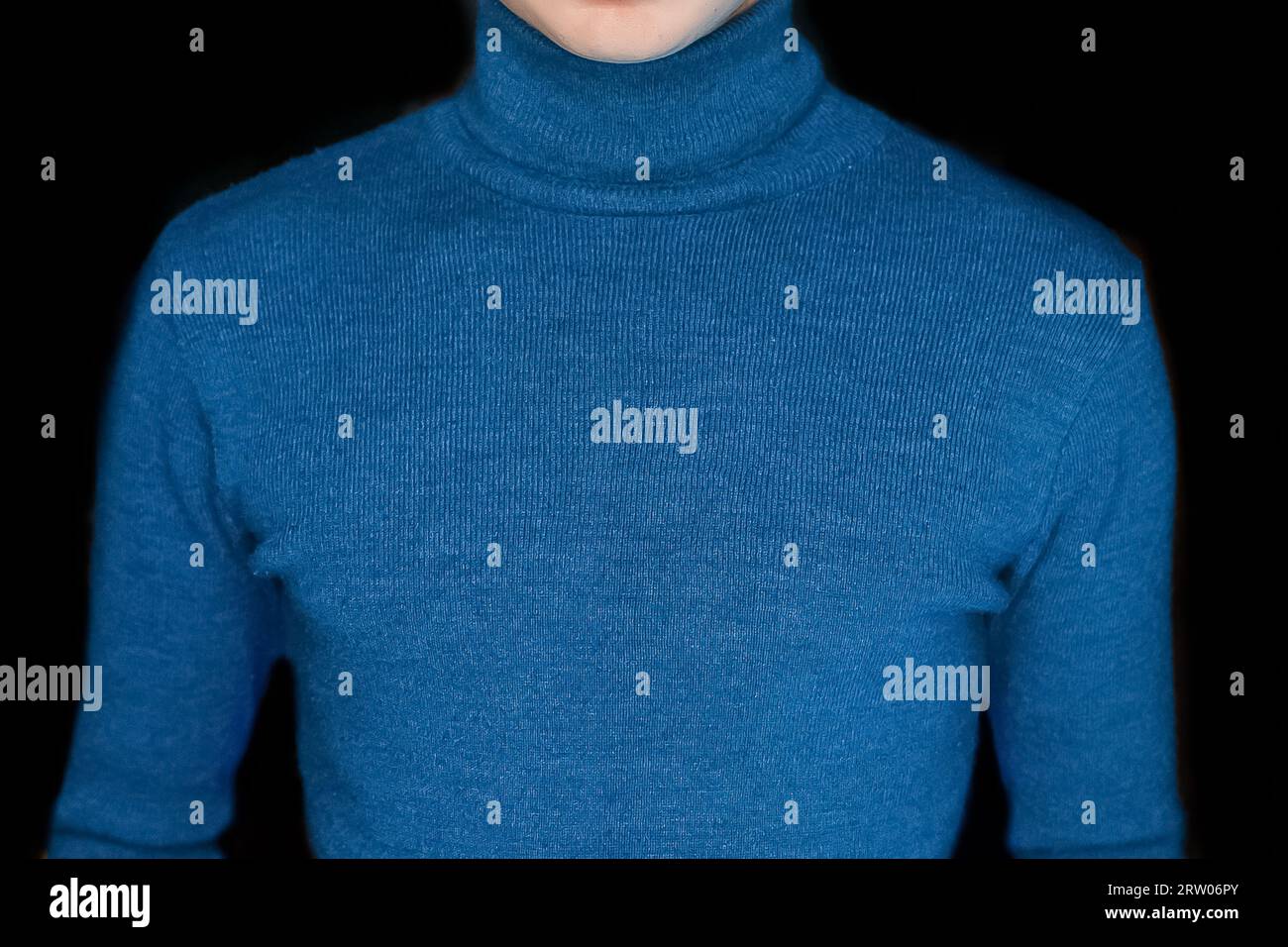 Skinny guy in blue turtleneck men's style of clothing on the black background, close up. Stock Photo