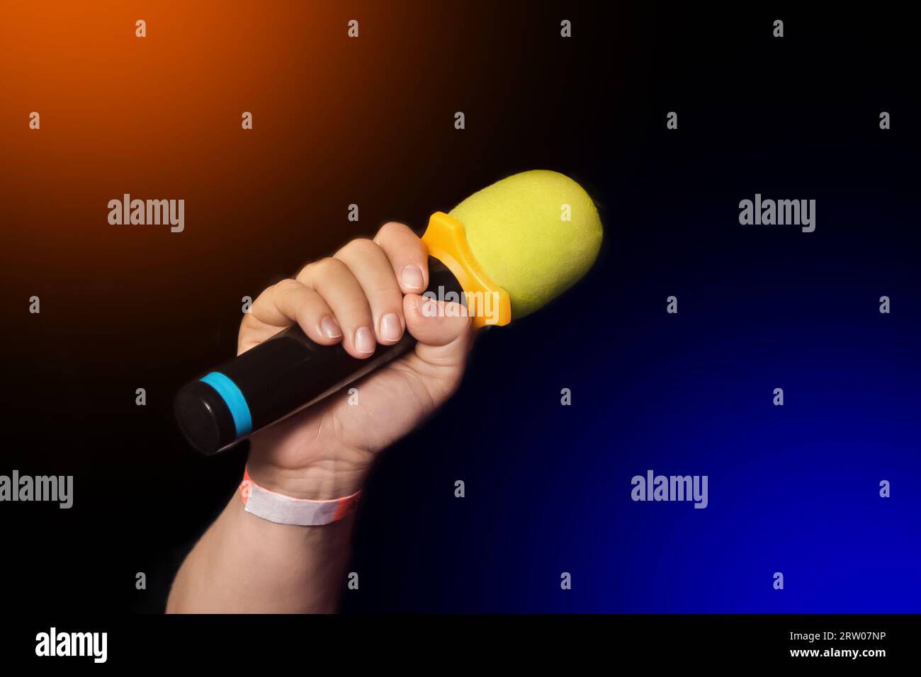 Female person hand close-up holding microphone professional karaoke singing equipment on black color background. Stock Photo