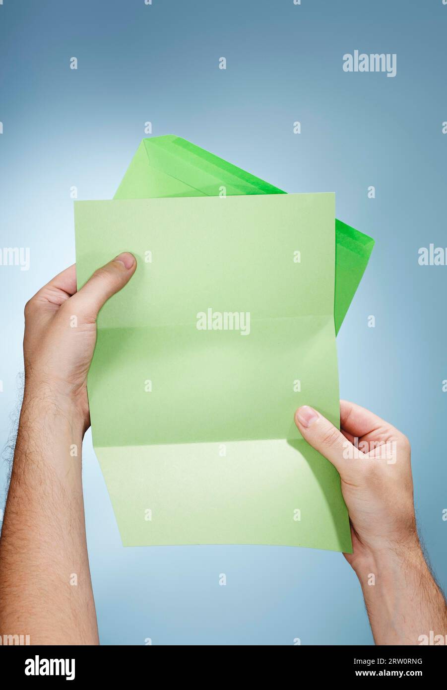 Man holding a green envelope and a blank green letter in his hands Stock Photo