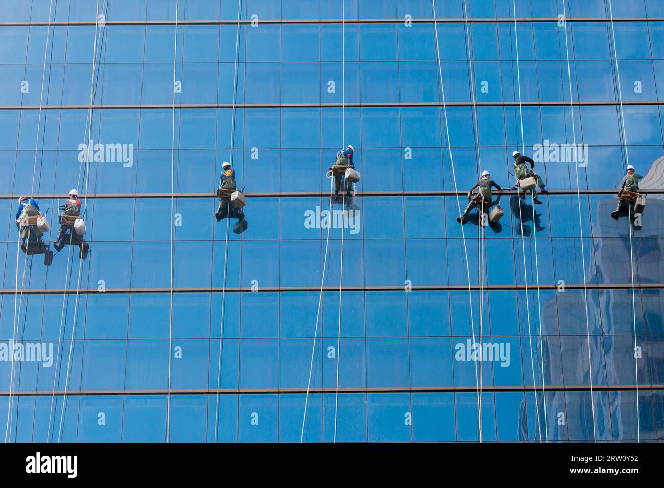 Laborers clean windows as a team on a skyscraper in downtown Seoul