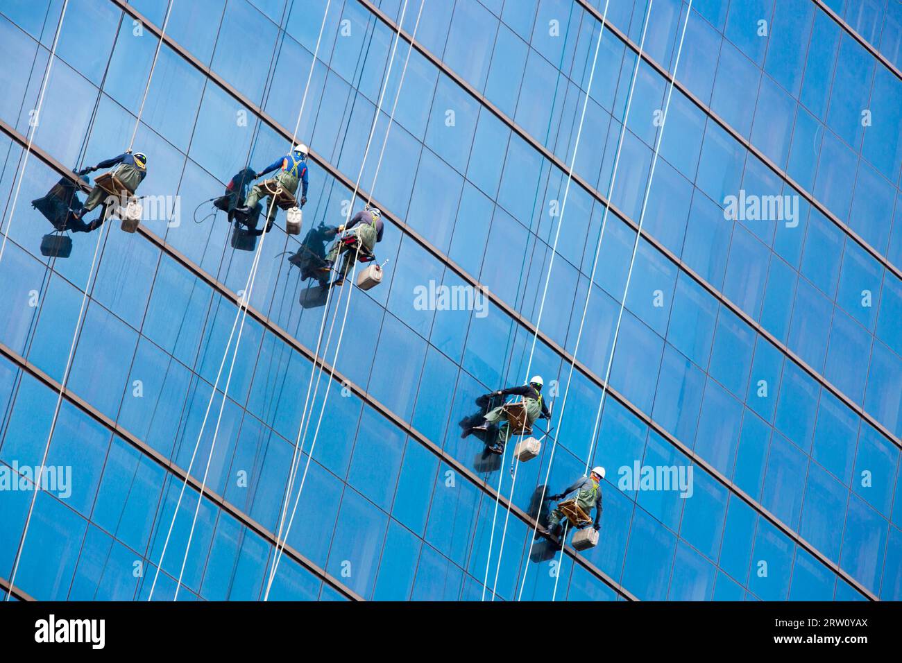 Laborers clean windows as a team on a skyscraper in downtown Seoul