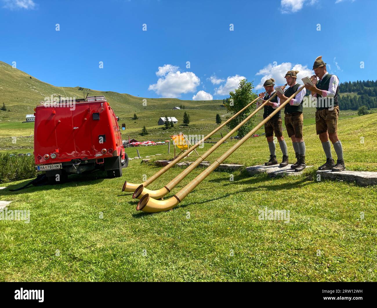 Alphorn blowers at the Trattberg Almfest on 15.8.23 with their vehicle, a converted fire engine, Salzburger Land, Austria Stock Photo