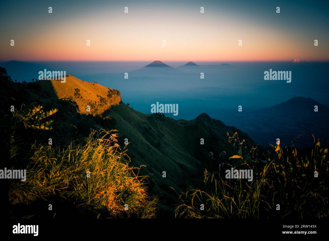 Photo of Mt. Merbabu and surrounding mountains in sunlight during sunrise near Yogya in central Java province in Indonesia. In this region, one can Stock Photo